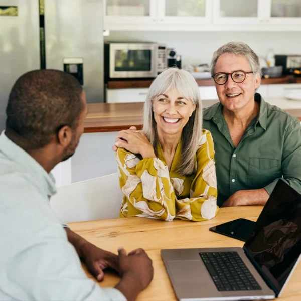 A couple around the age of 65 sitting at a table with a Medicare expert discussing their options